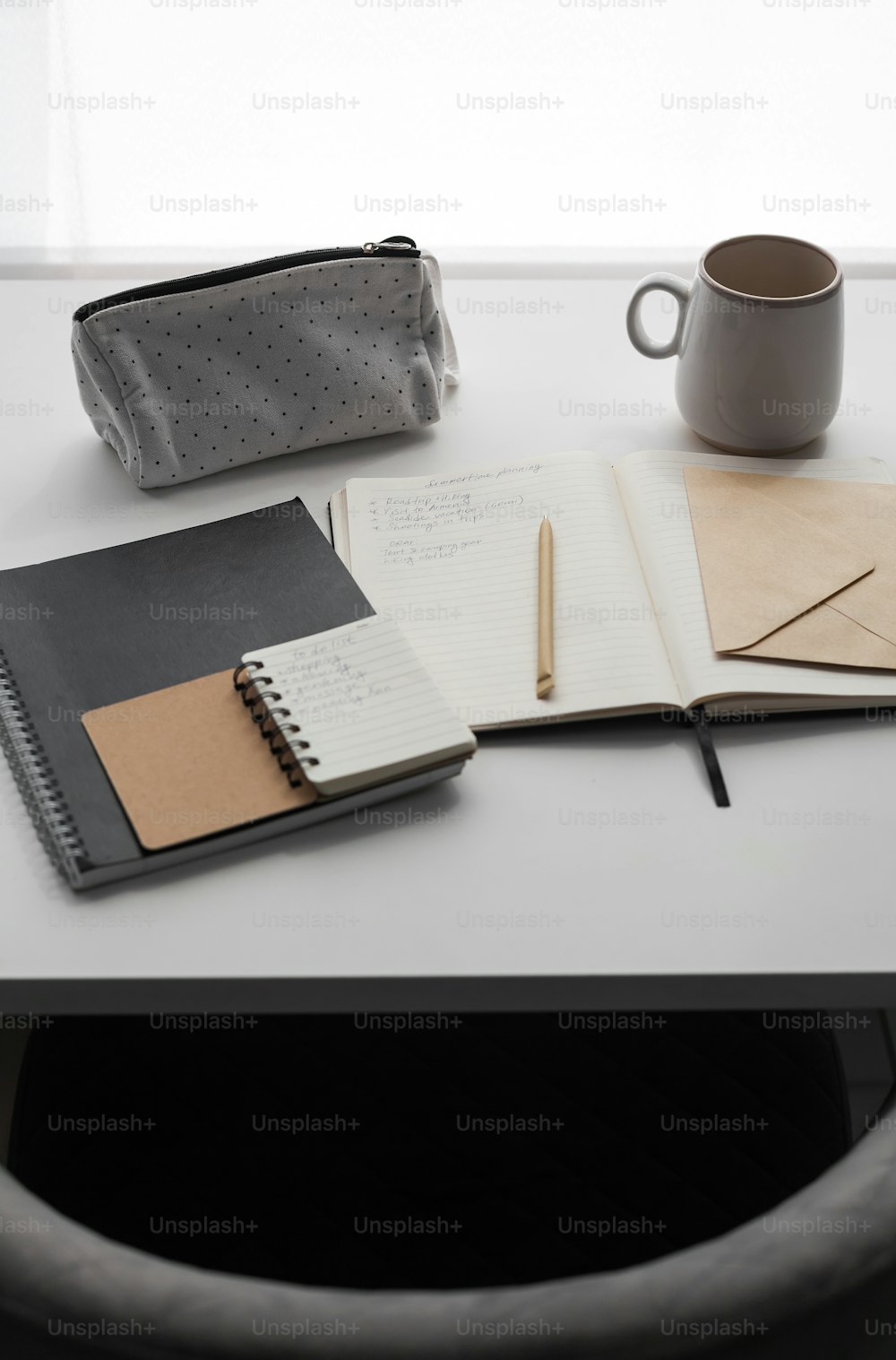 a desk with a notebook, pen and a cup of coffee