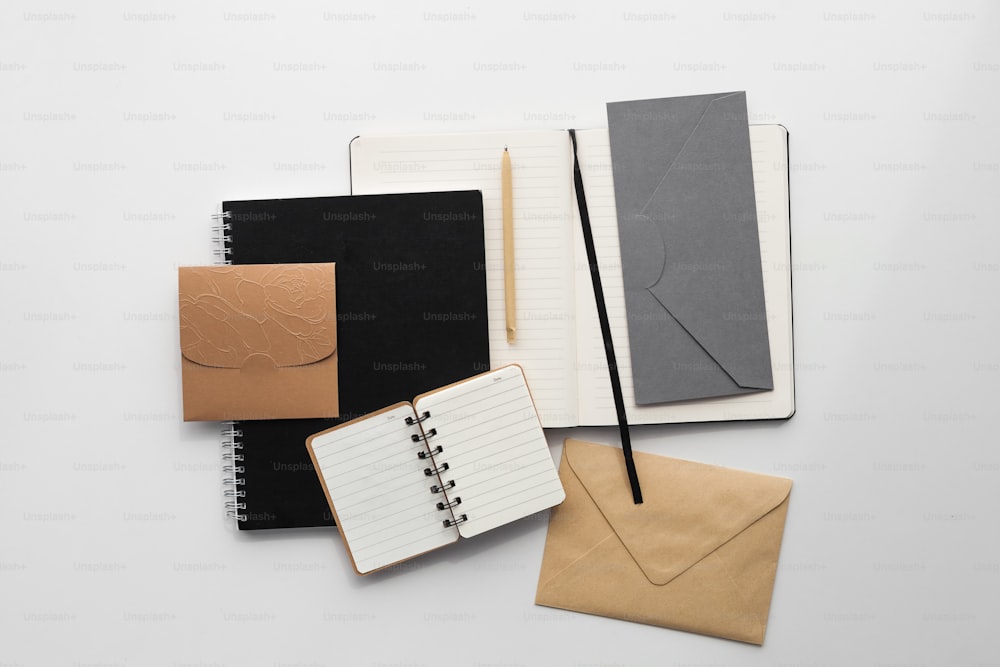 Notizbuch, Stift und Umschlag auf weißer Fläche
