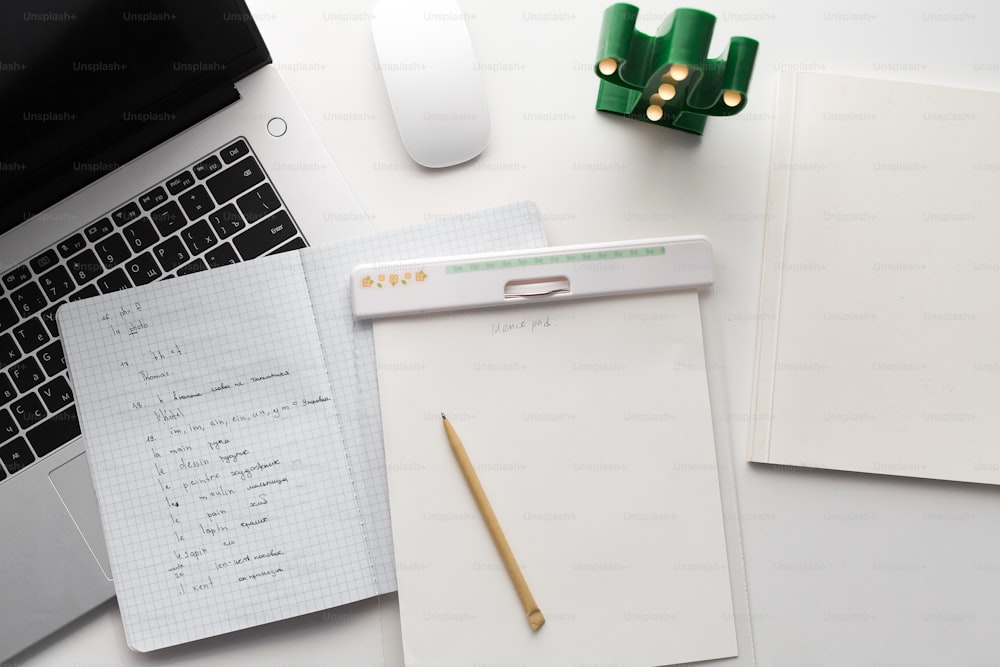 ein weißer Schreibtisch mit einem Laptop neben einem Notebook