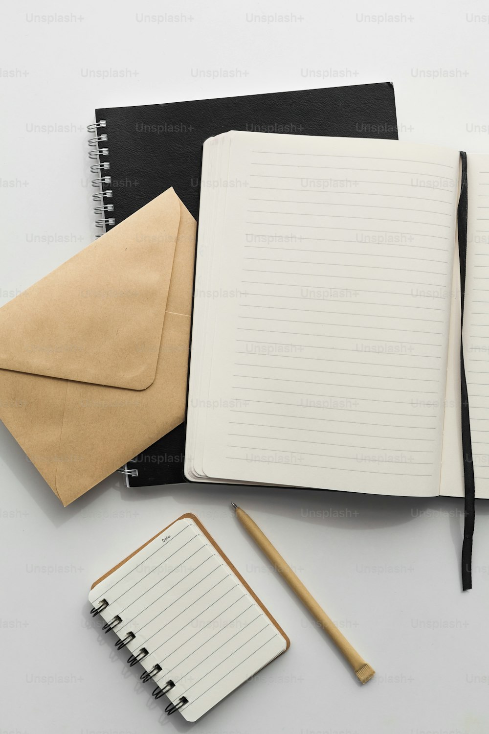 a notepad, pen, notebook, and envelope on a table