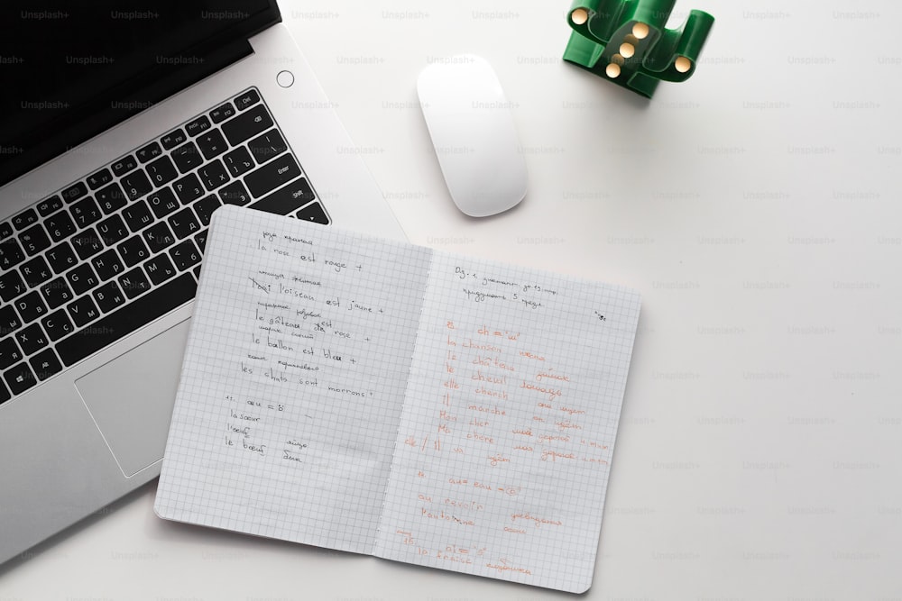 a notebook with writing on it next to a laptop