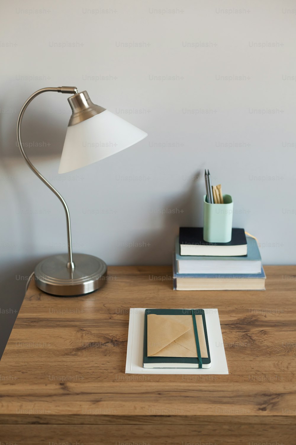 ein Schreibtisch mit einer Lampe und ein paar Büchern darauf