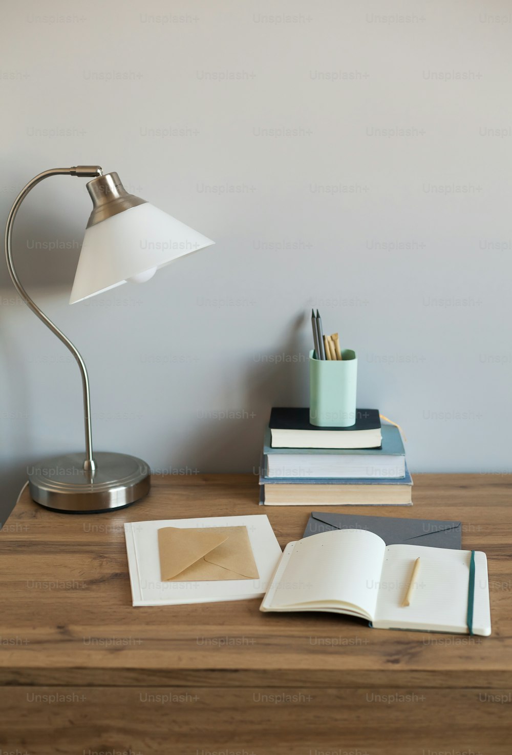 a desk with a lamp, books, and a cup on it