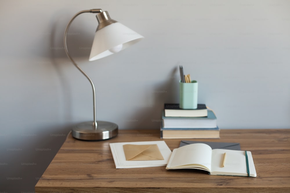 a desk with a lamp, books, and a cup on it