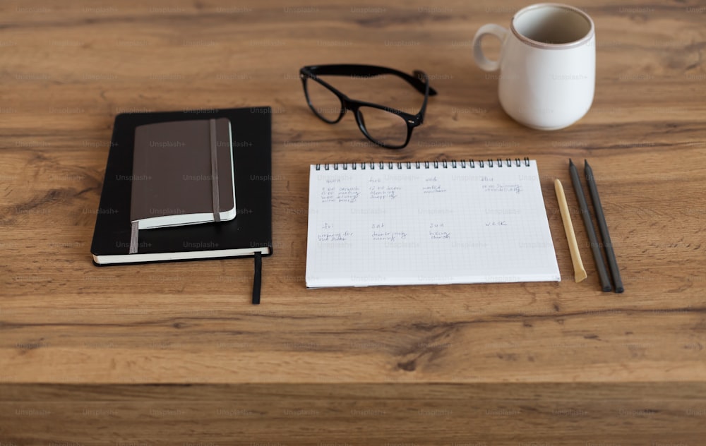 a notepad, pen, glasses, and a notebook on a table