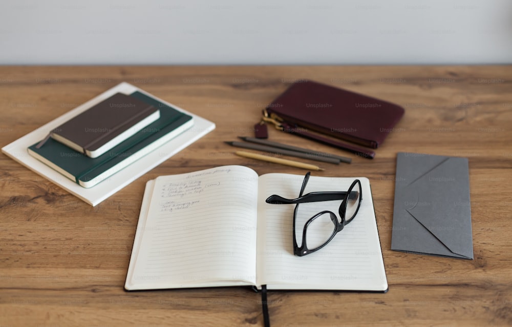 ein Notizbuch, ein Stift, eine Brille und ein Notizbuch auf einem Tisch