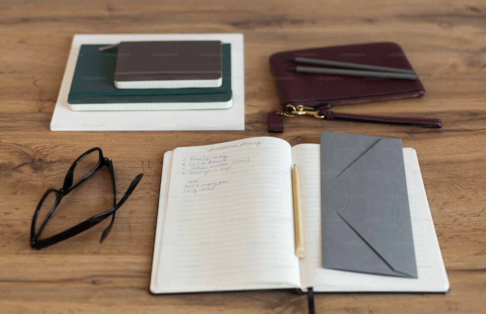 a notebook, glasses, pen, and notebook on a table