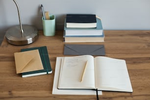 a wooden table topped with notebooks and a lamp