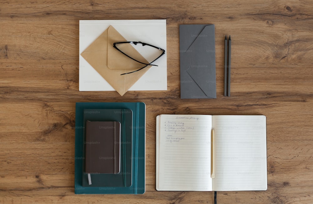 um bloco de notas, caneta, caderno e papel sobre uma mesa de madeira