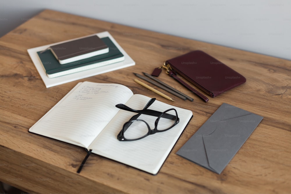 a wooden table topped with a notebook and glasses