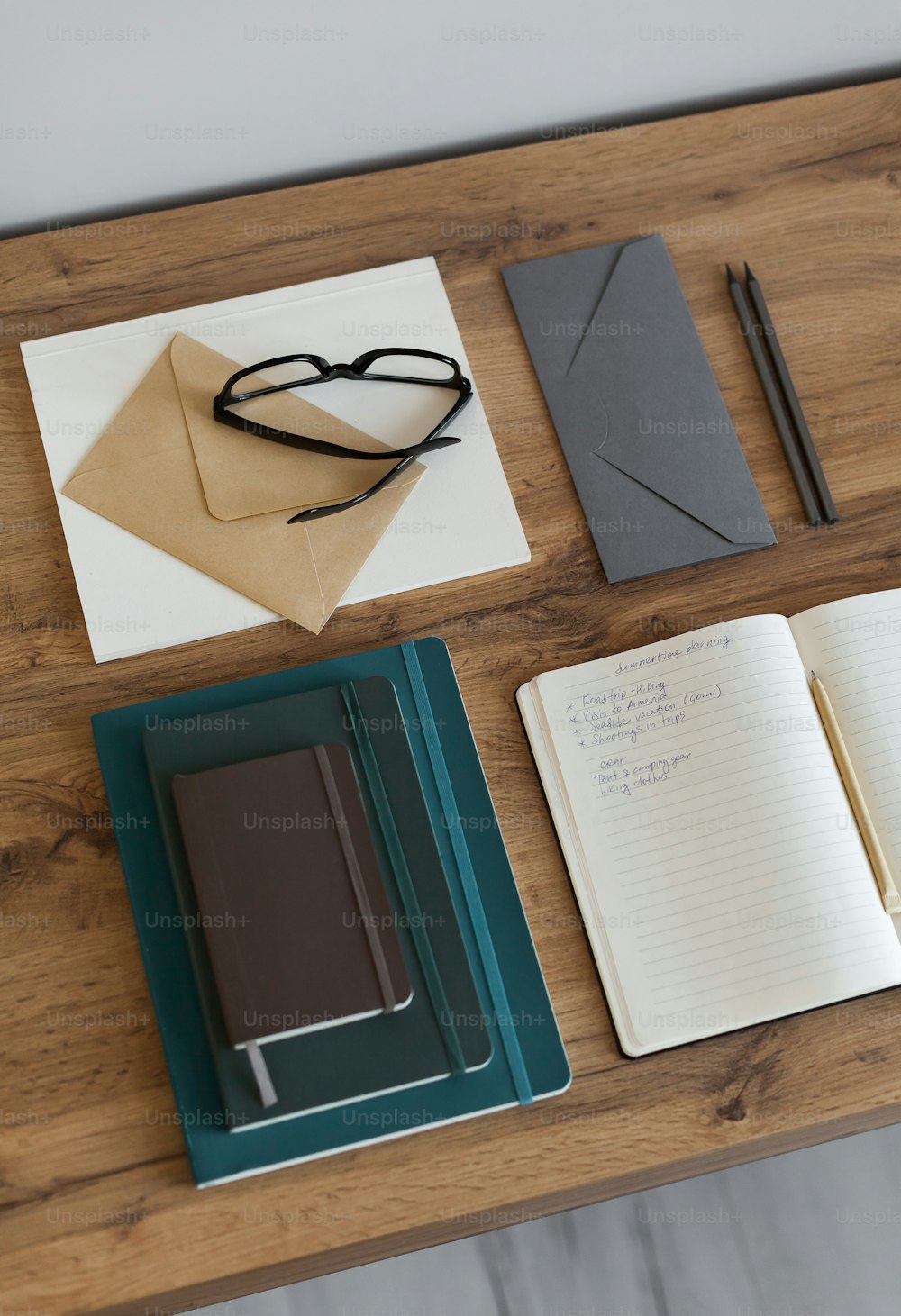 a wooden table topped with notebooks and a pair of glasses