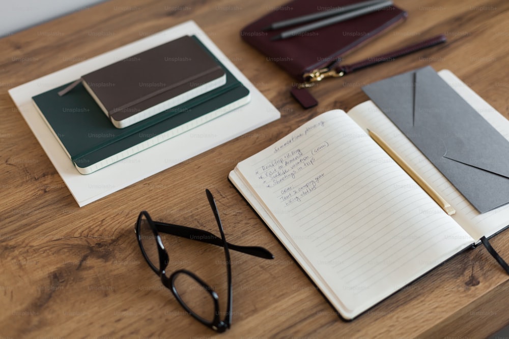 a wooden table topped with notebooks and glasses
