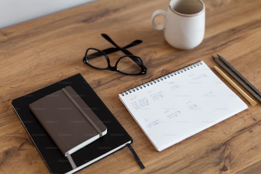 a notepad, pen, glasses, and a cup of coffee on a table