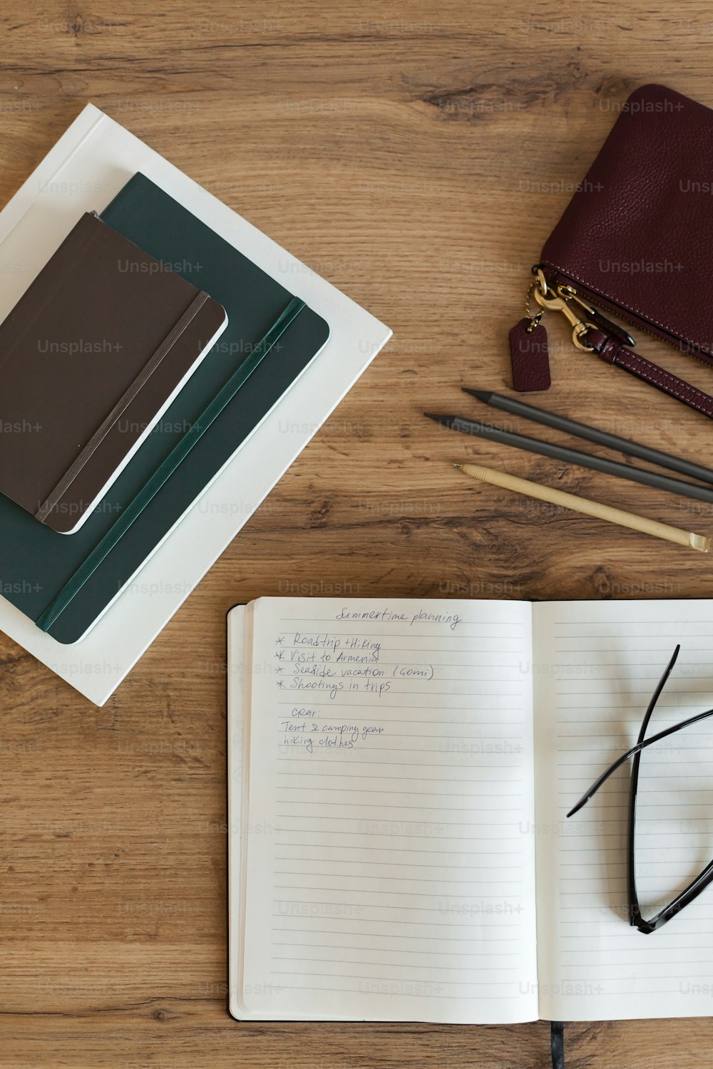 a notebook with a pen, glasses, and pencils on a table