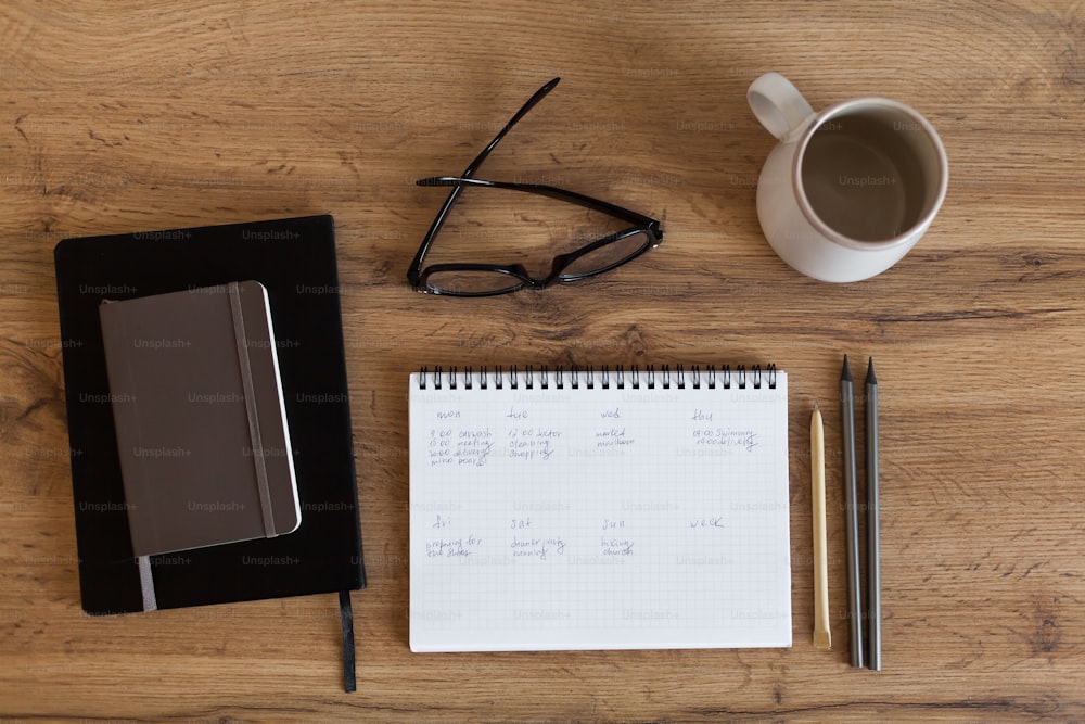 a notepad, pen, glasses, eyeglasses and a cup of coffee