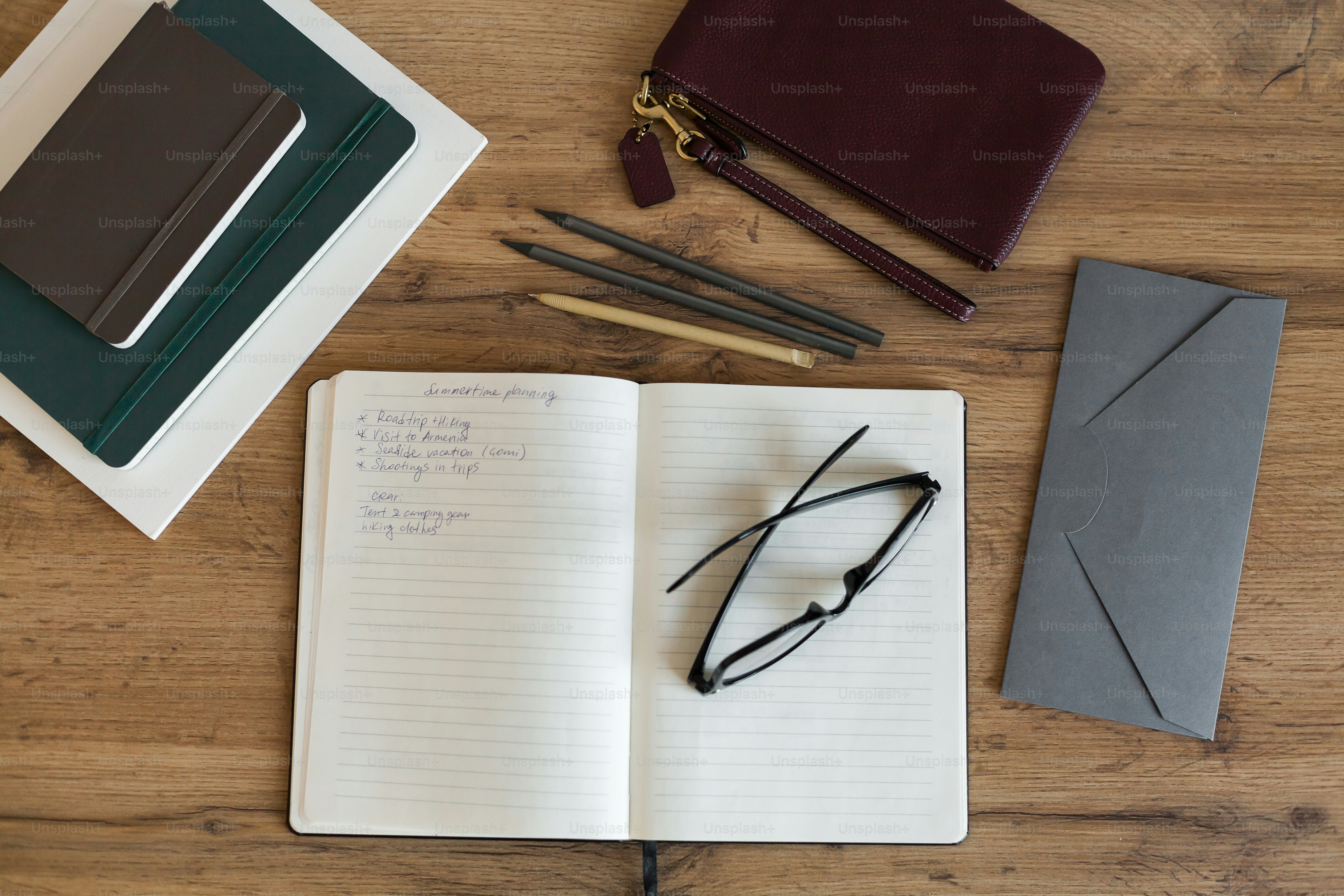 a notebook, pen, glasses, and other items on a table