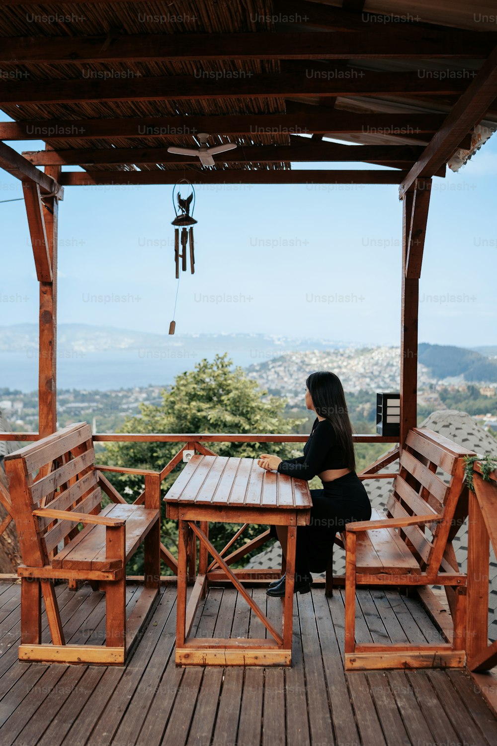 a woman sitting at a wooden table on top of a wooden deck