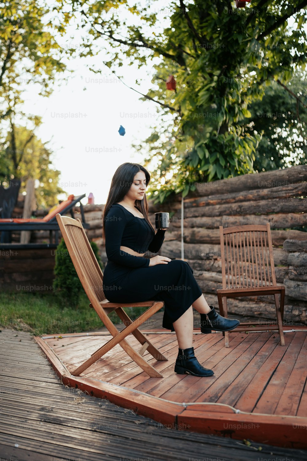 a woman sitting on a wooden chair holding a glass of wine