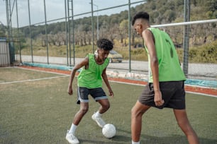 Un couple de jeunes hommes donnant des coups de pied autour d’un ballon de football