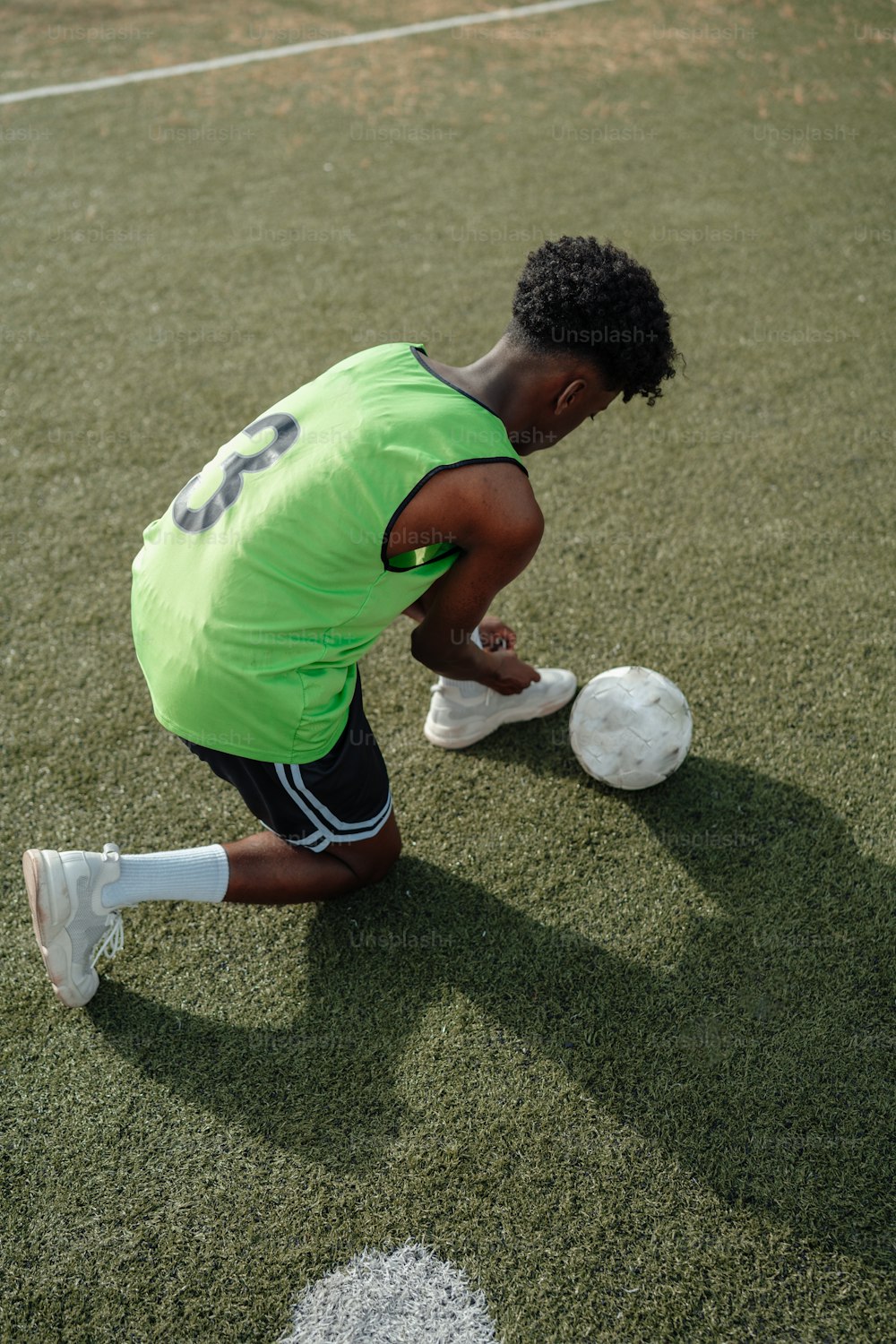 Una persona arrodillada con una pelota de fútbol