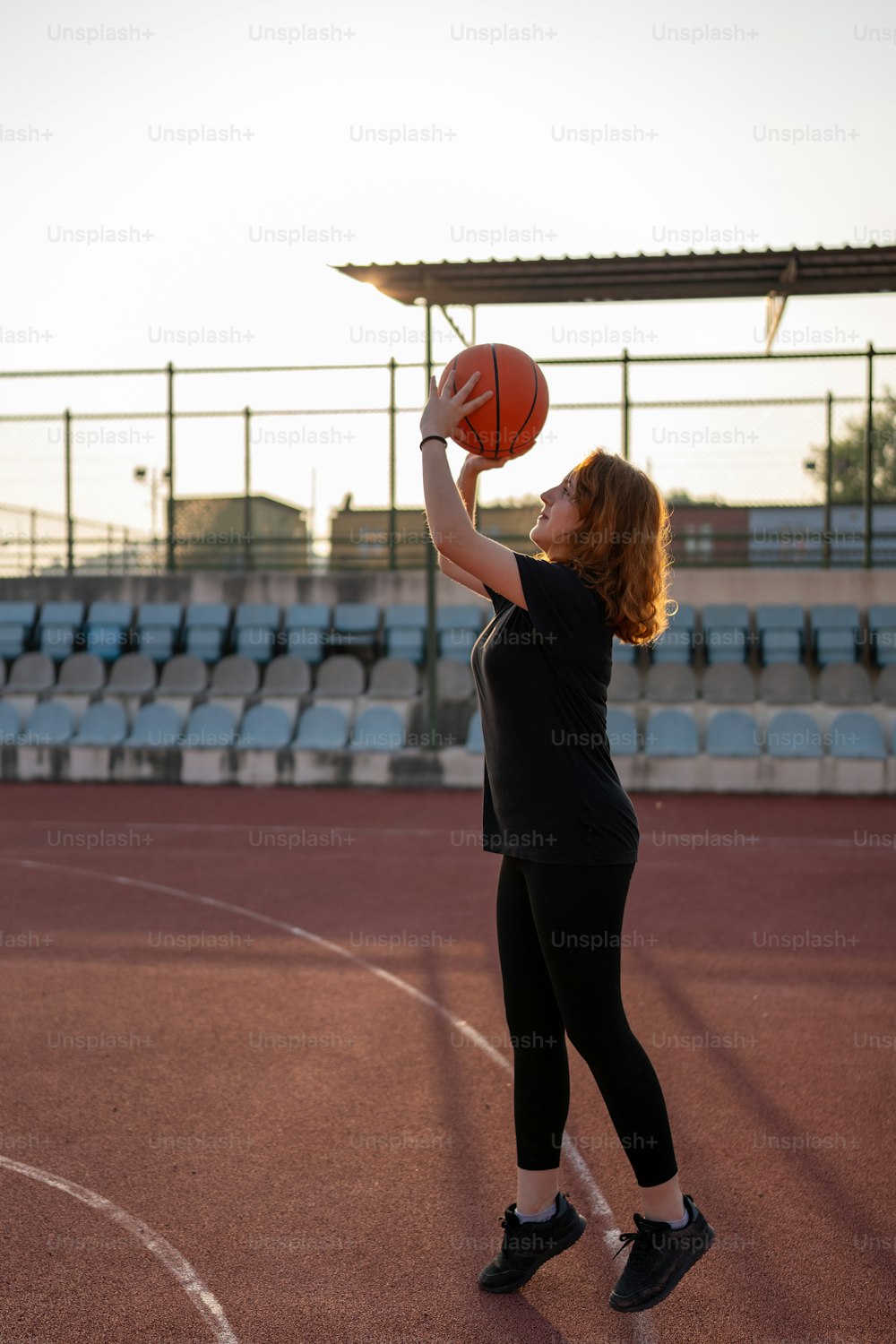 Una mujer sosteniendo una pelota de baloncesto en una cancha de baloncesto