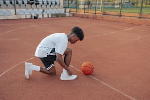 a man kneeling down next to a basketball on a court
