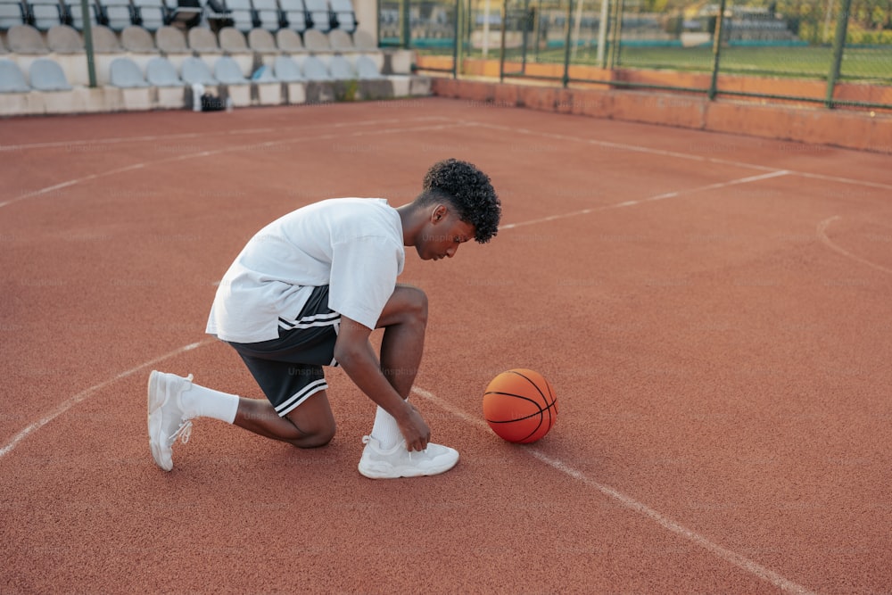 a man kneeling down next to a basketball on a court
