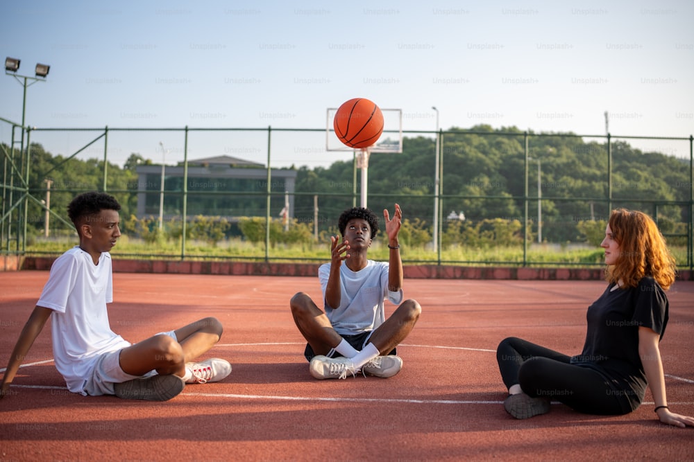 eine gruppe junger leute, die auf einem basketballplatz sitzen