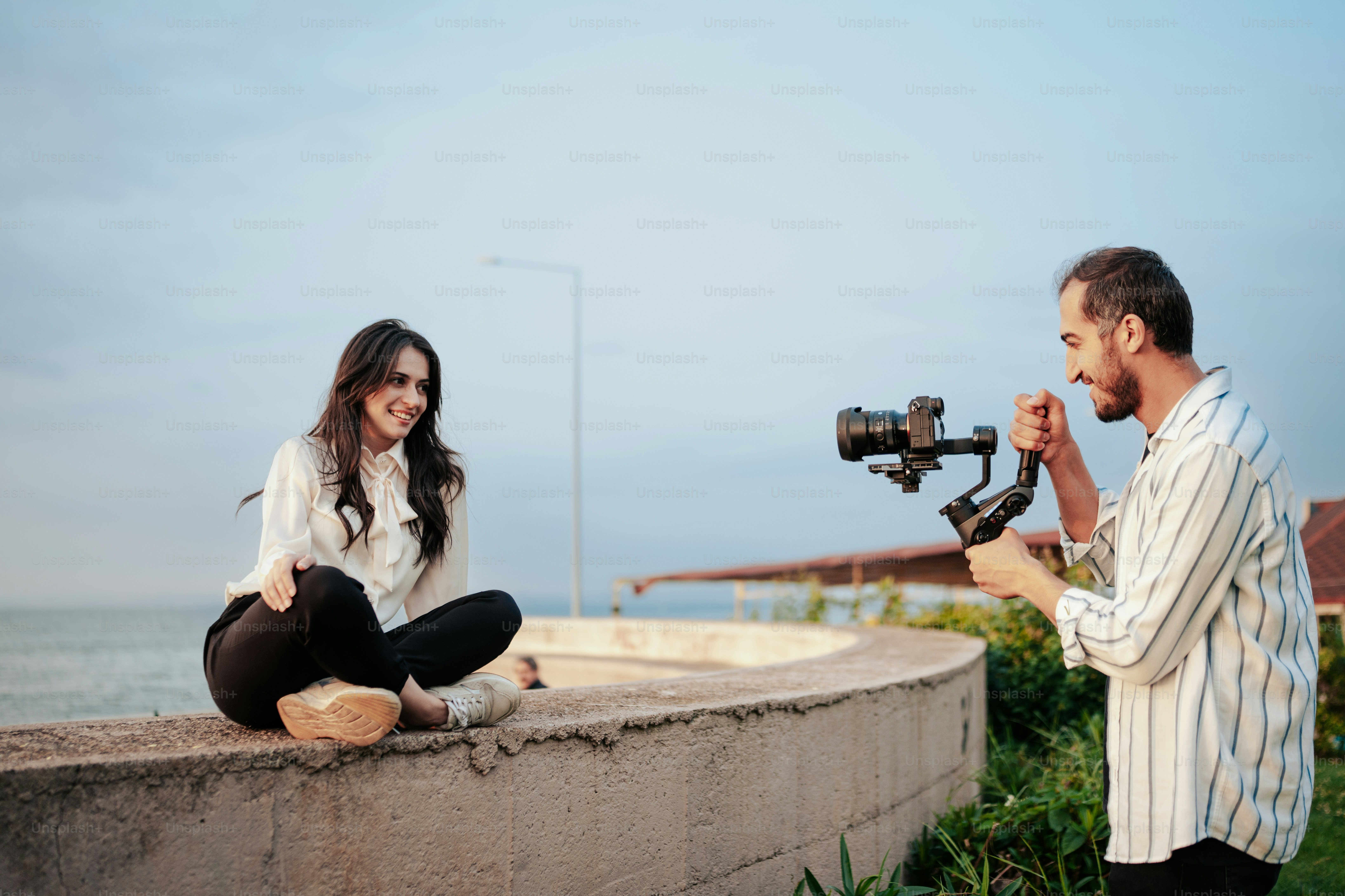 a man and a woman sitting on a wall with a camera