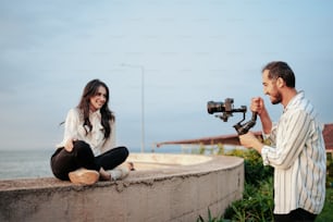a man and a woman sitting on a wall with a camera