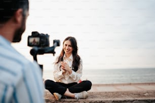 a woman sitting on the ground in front of a camera