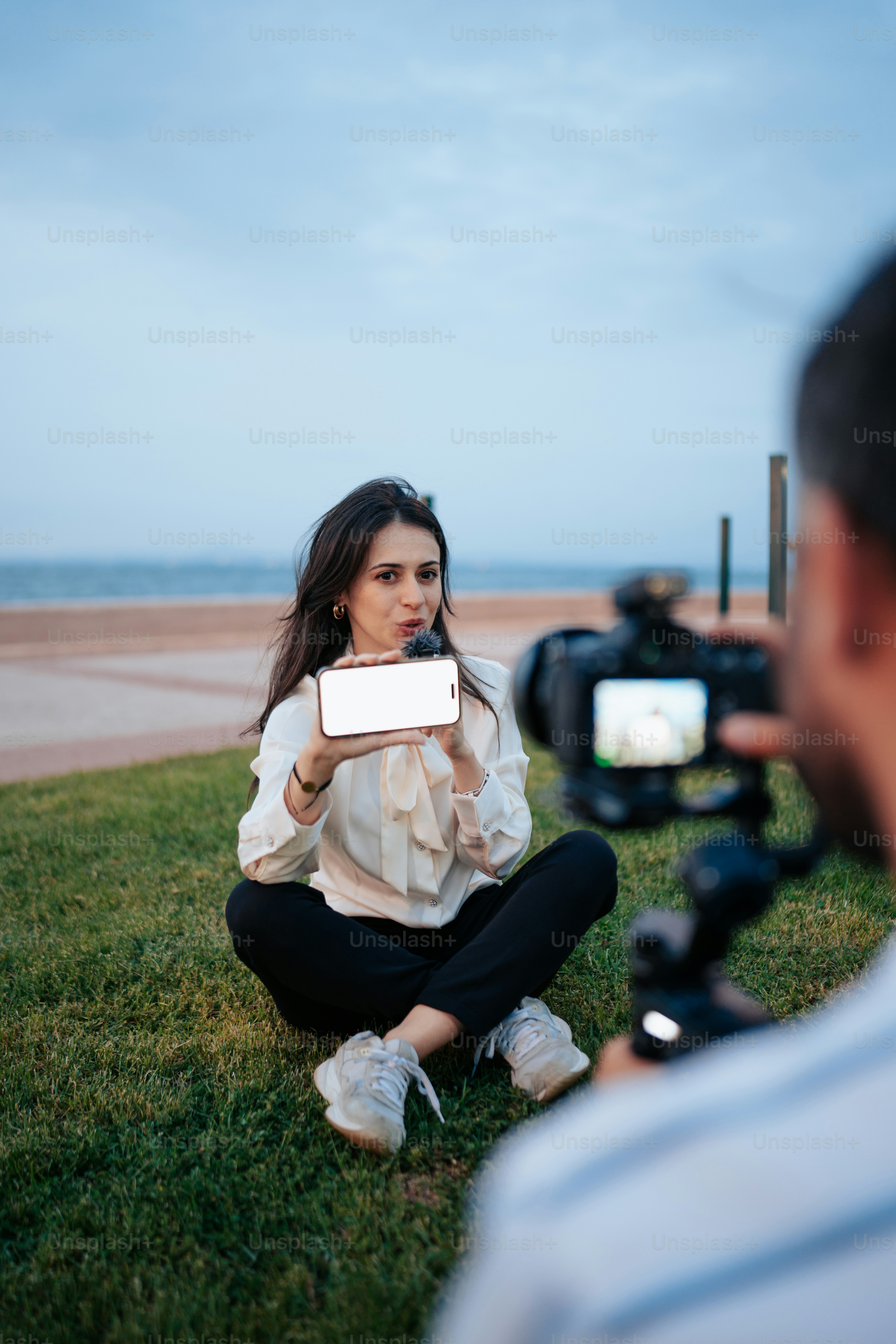 a woman sitting in the grass holding a mirror