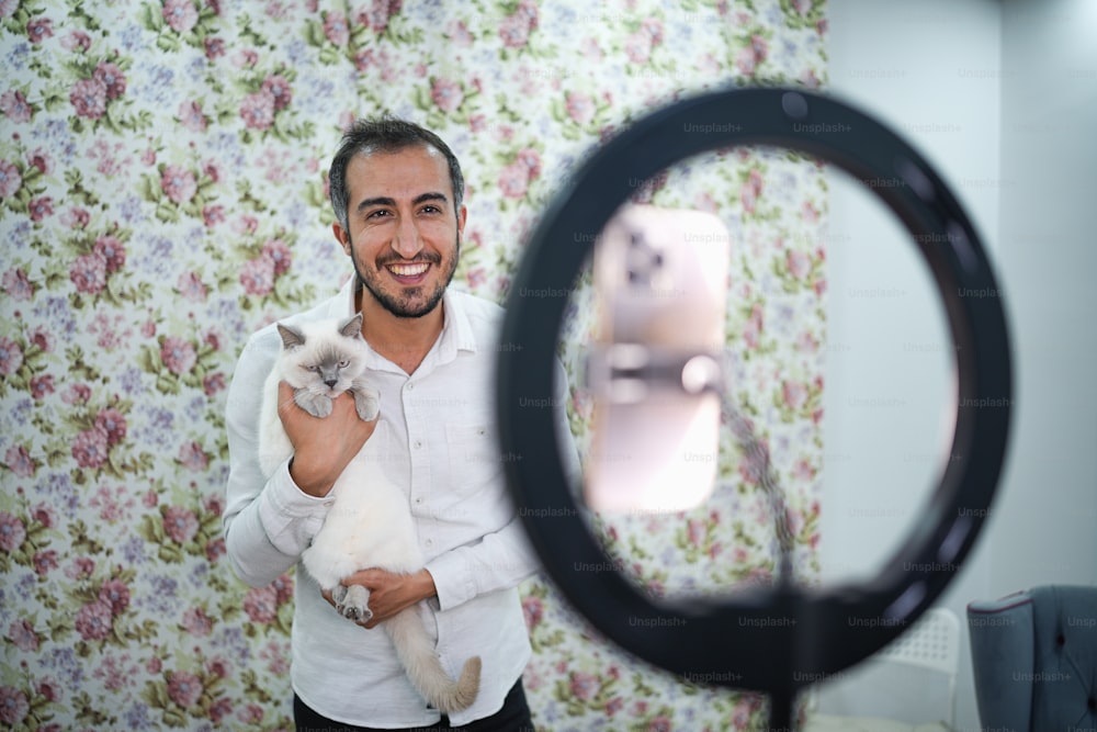 Un hombre sosteniendo un gato frente a una cámara