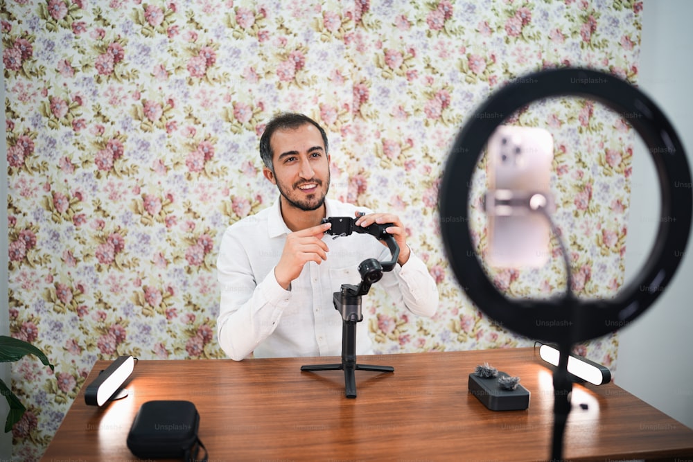 um homem sentado em uma mesa com uma câmera