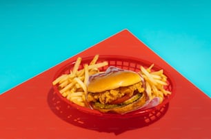 a chicken sandwich and french fries on a red plate