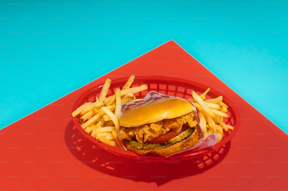 a chicken sandwich and french fries on a red plate