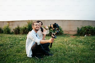 Un homme et une femme assis dans l’herbe avec une caméra