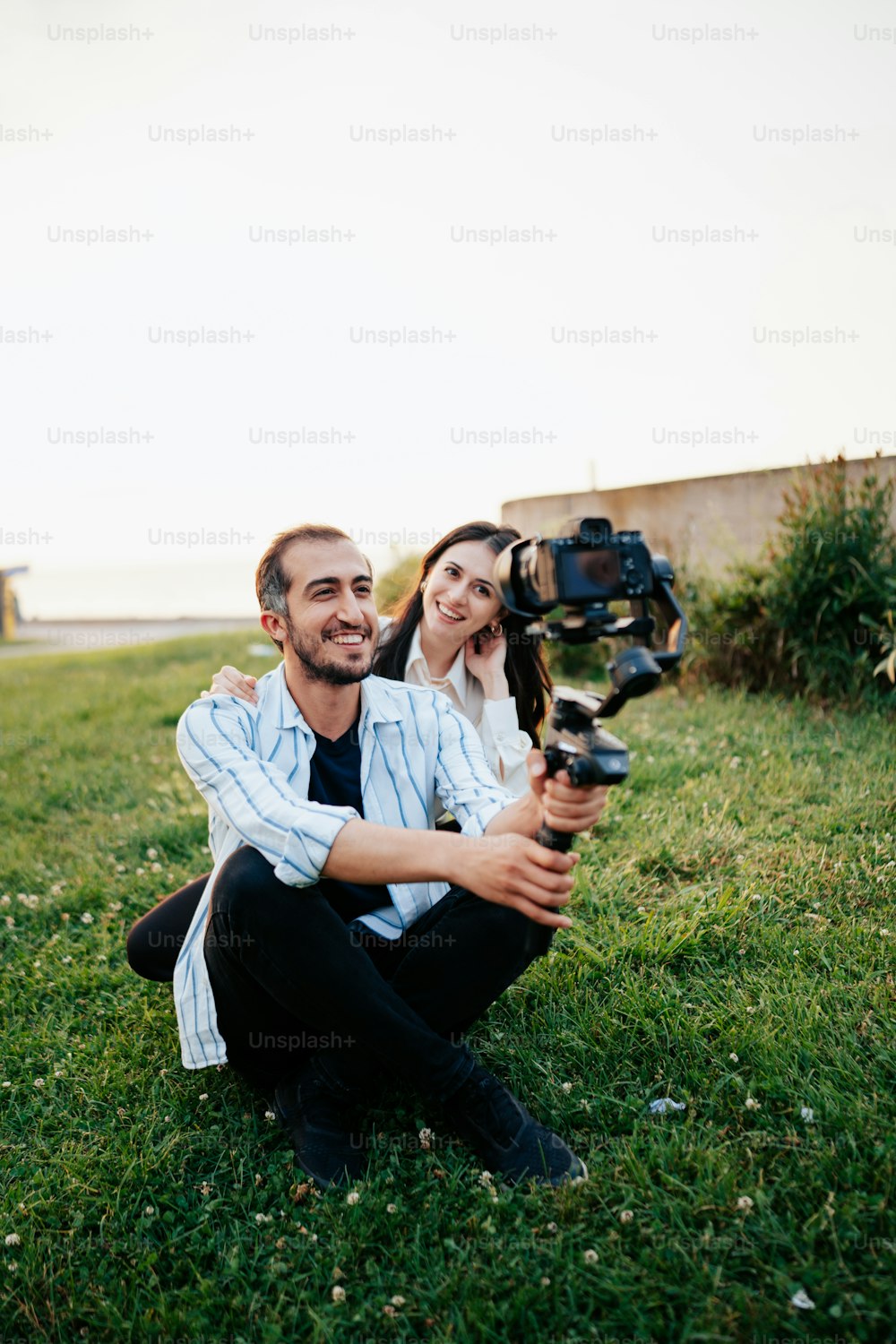 カメラを持って草の中に座っている男女
