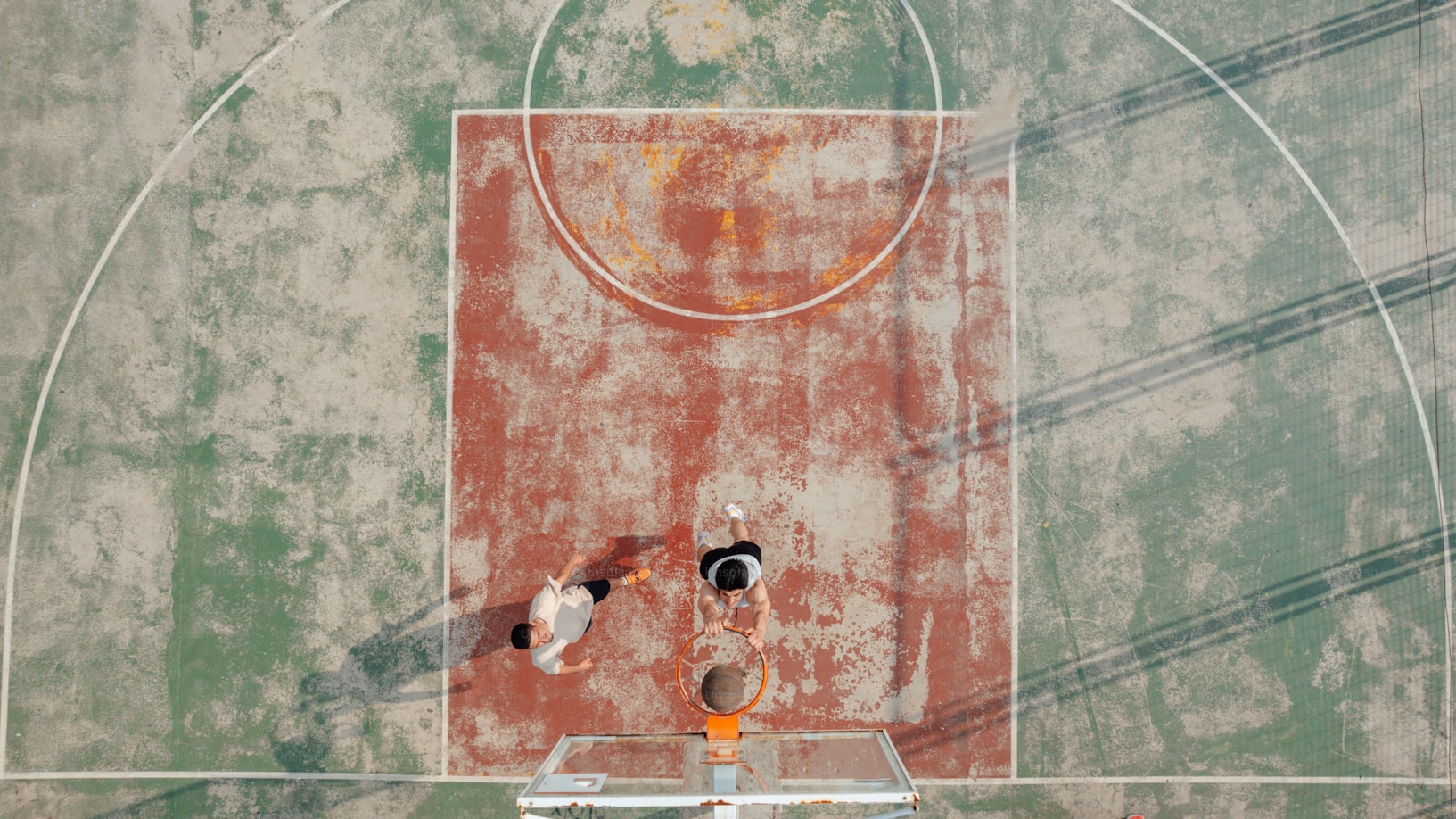 Two people playing in a basketball court  Two people playing in a basketball court