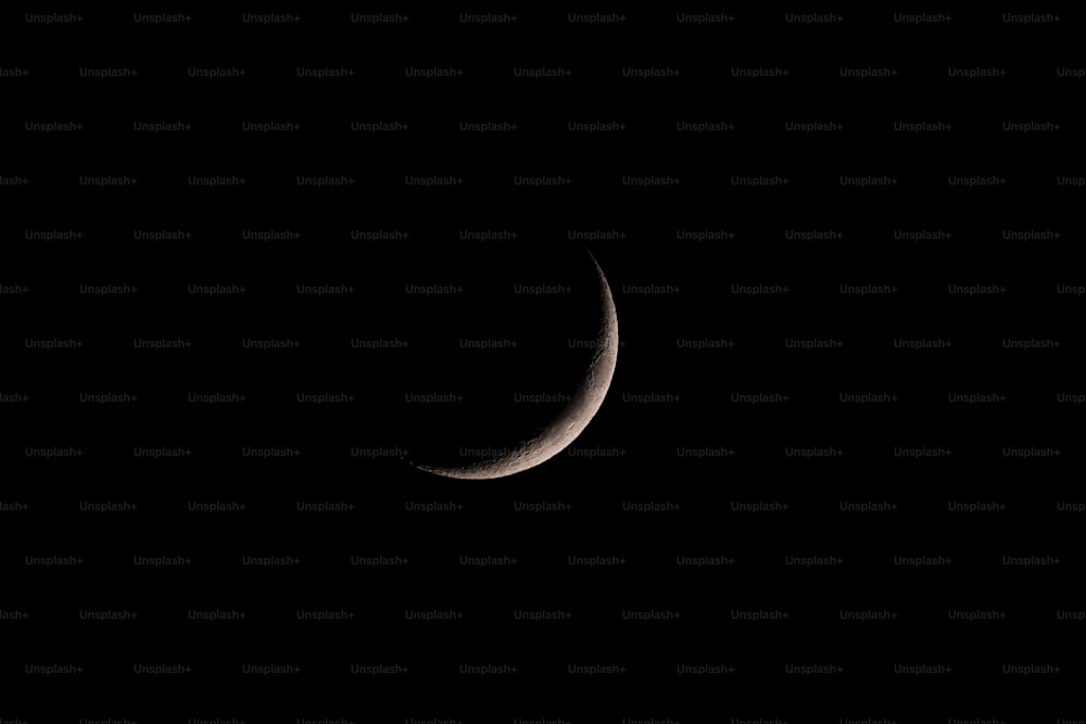 Un croissant de lune est vu dans le ciel sombre