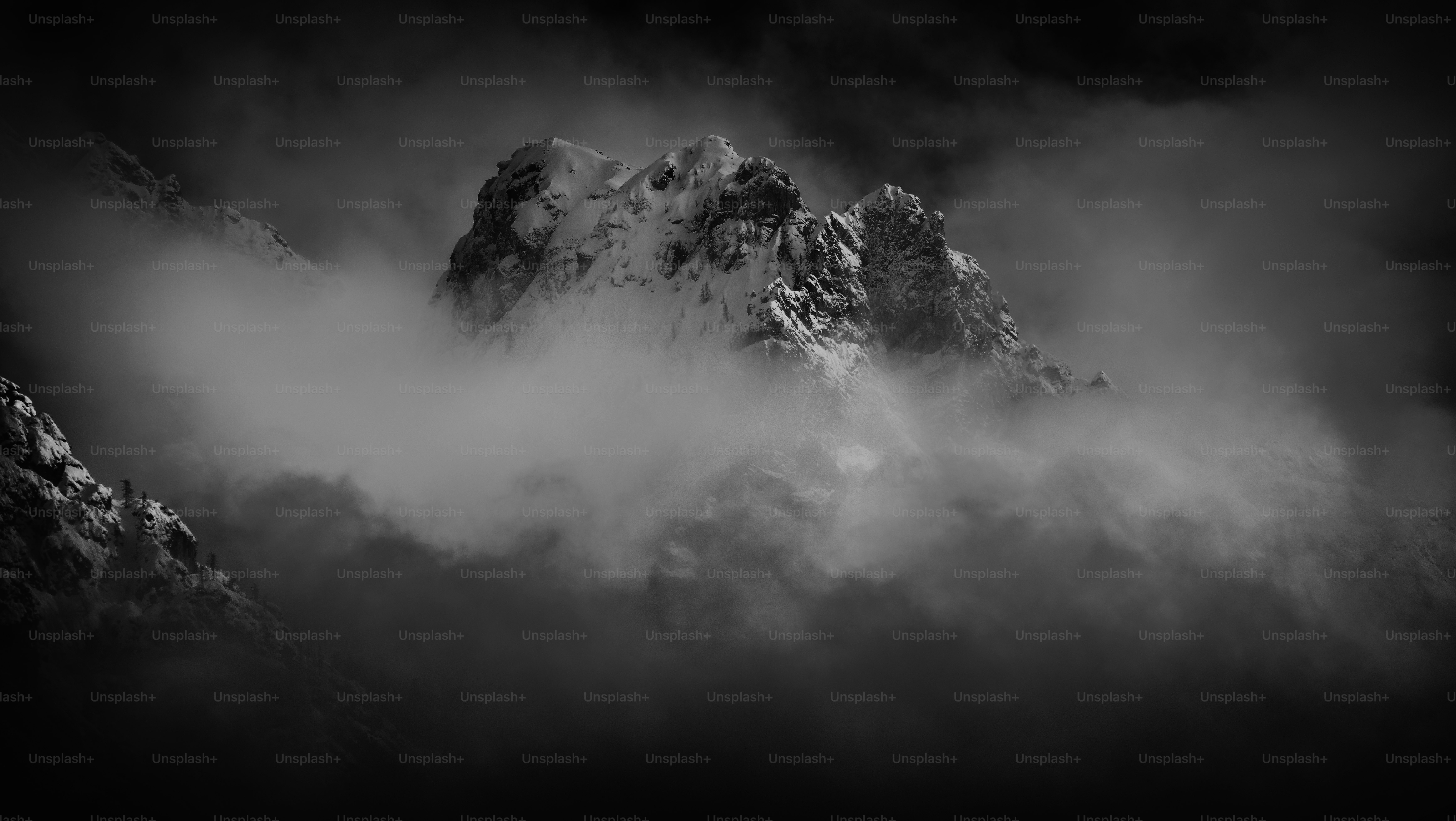 a black and white photo of a mountain covered in clouds