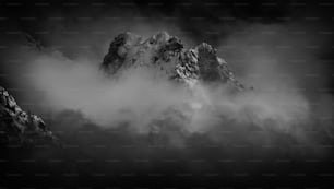 a black and white photo of a mountain covered in clouds