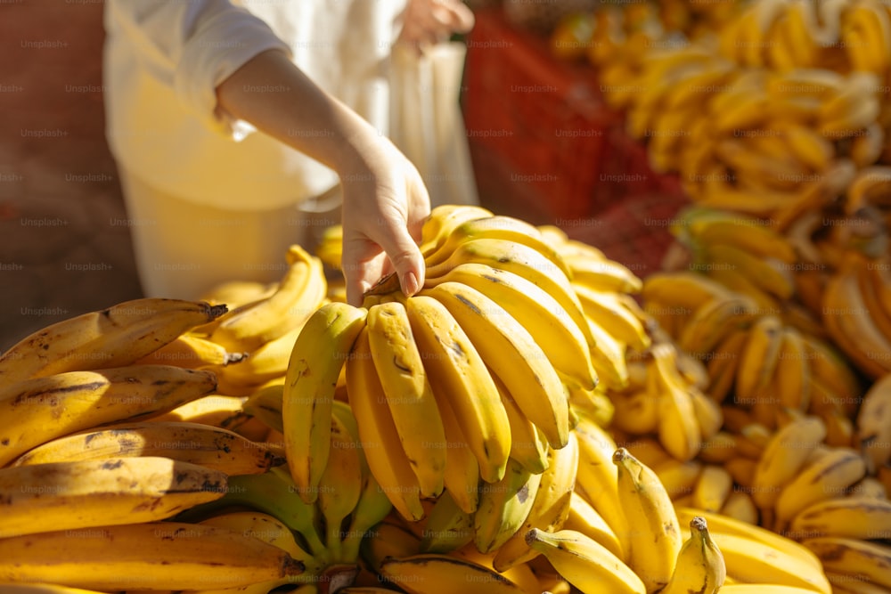 a person reaching for a bunch of bananas