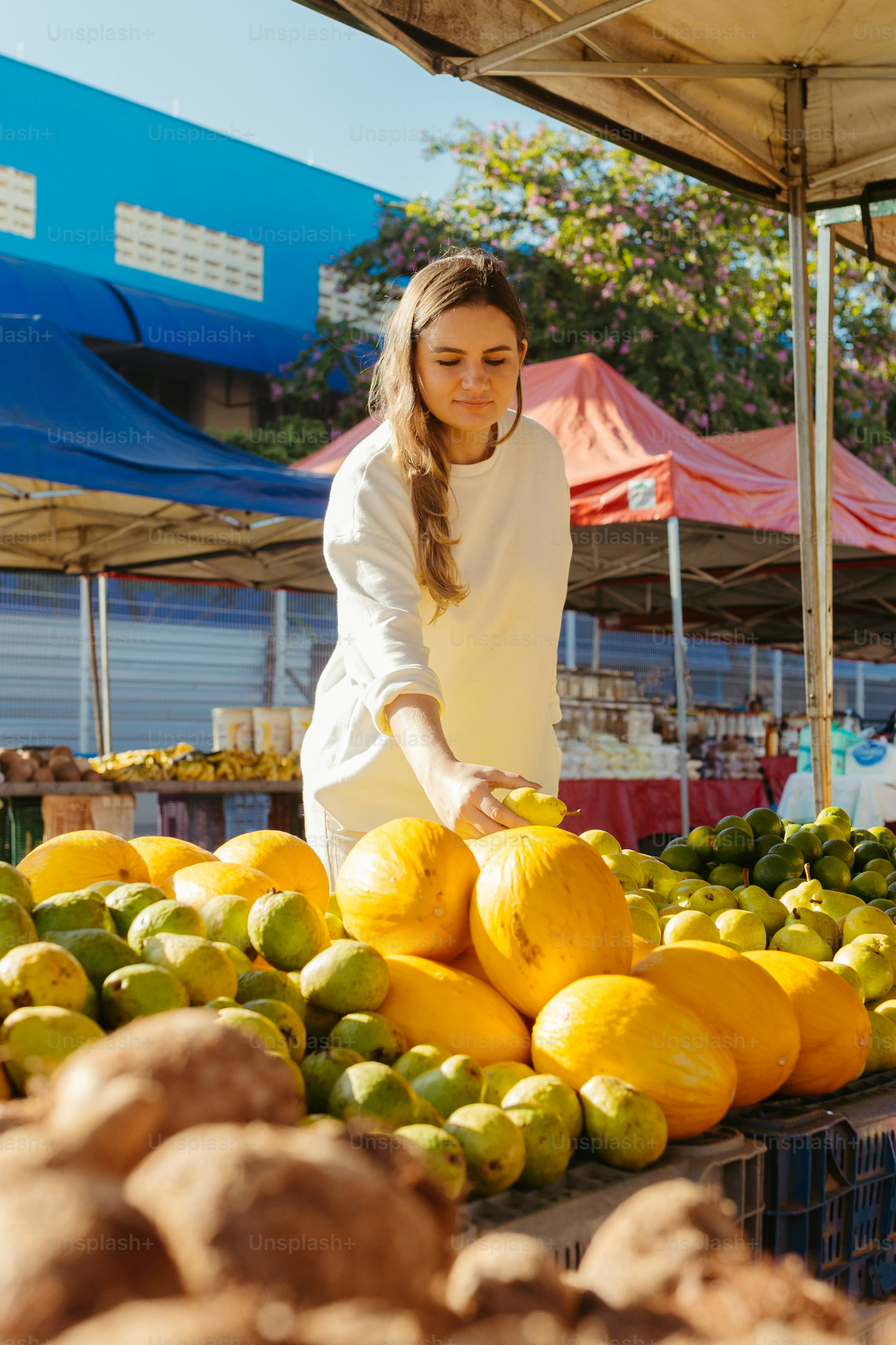 a woman standing in front of a pile of fruit