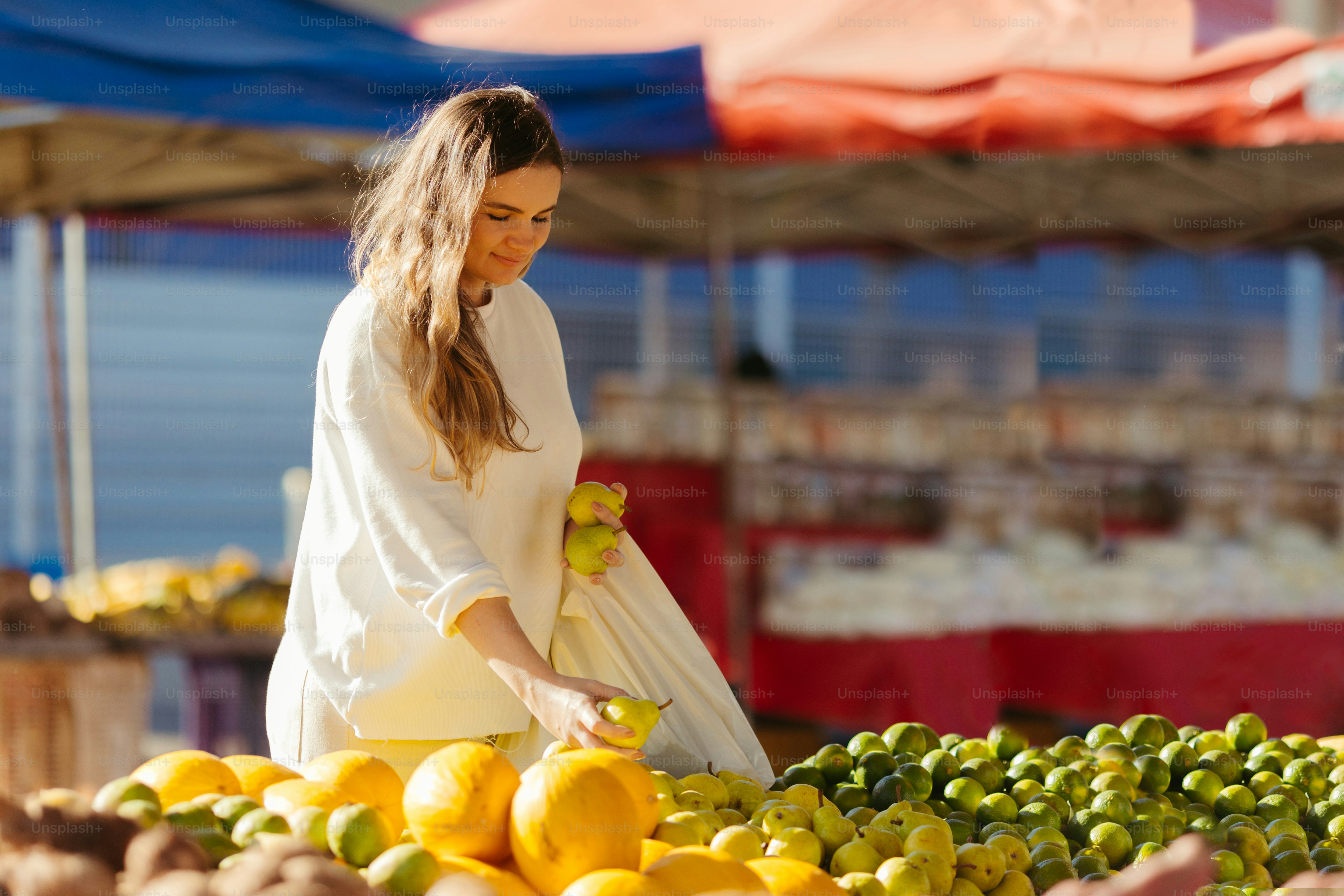 a woman standing in front of a pile of fruit