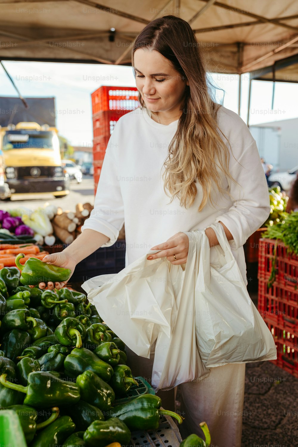 a woman holding a bag of green peppers