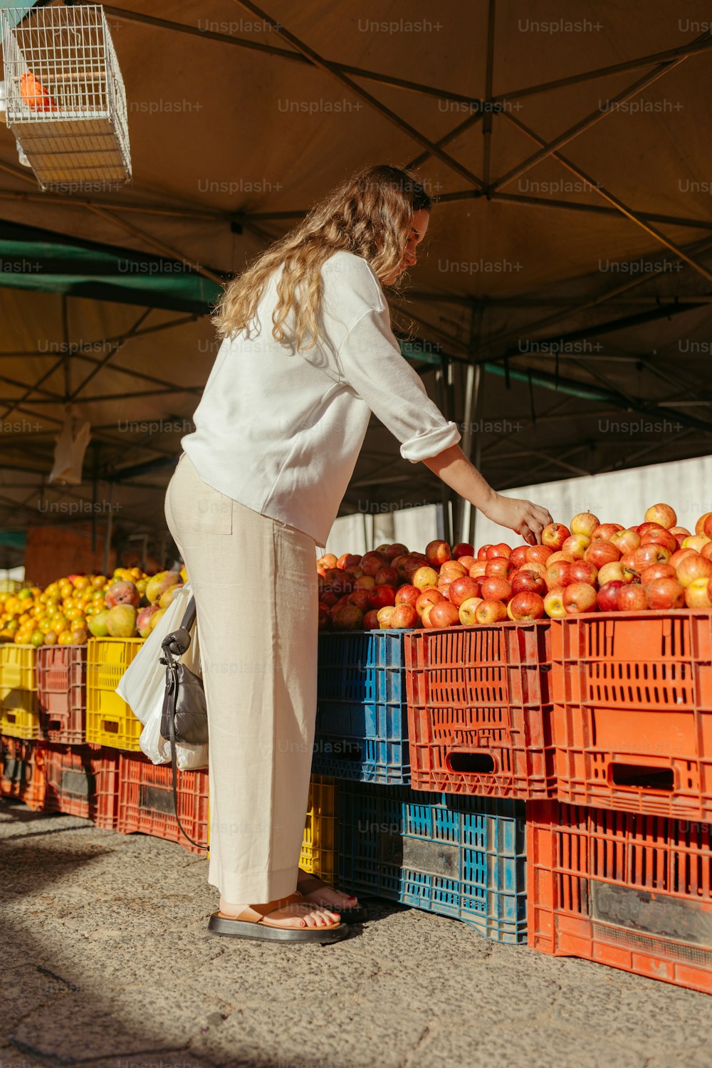 Una mujer está recogiendo naranjas de un puesto de frutas