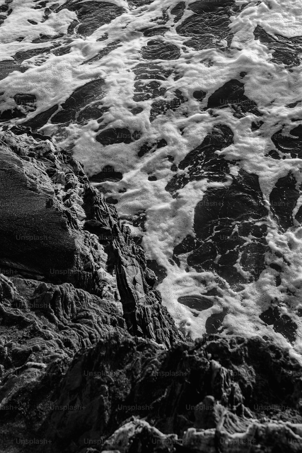 a black and white photo of waves crashing on rocks