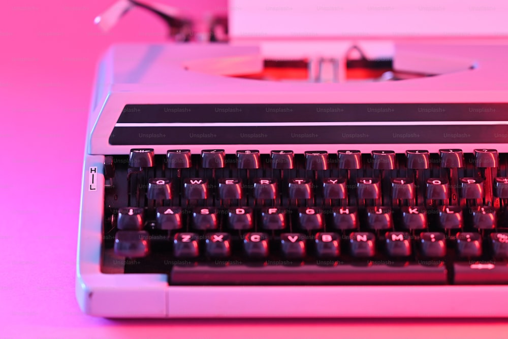 Un primo piano di una vecchia macchina da scrivere su uno sfondo rosa