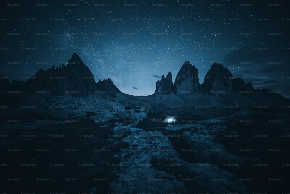 Un cielo nocturno con estrellas sobre una cadena montañosa